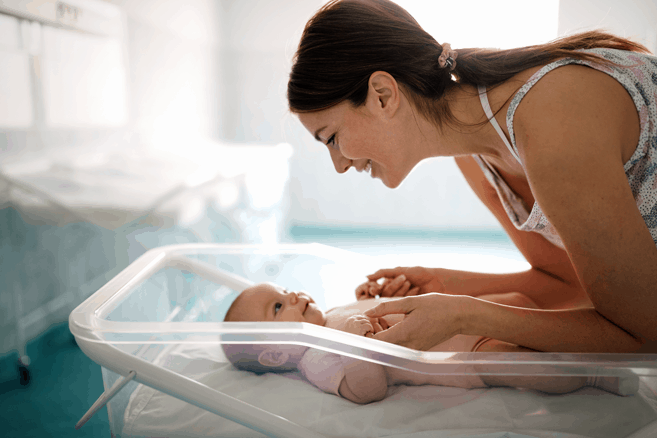 Jeune mère s'occupant de son nouveau-né en chambre privée à l'hôpital après la naissance