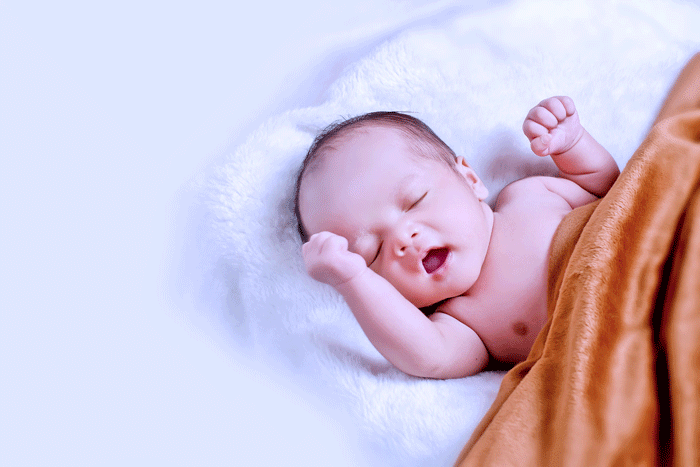 Nouveau-né Léonie en train de dormir avec une couverture orange