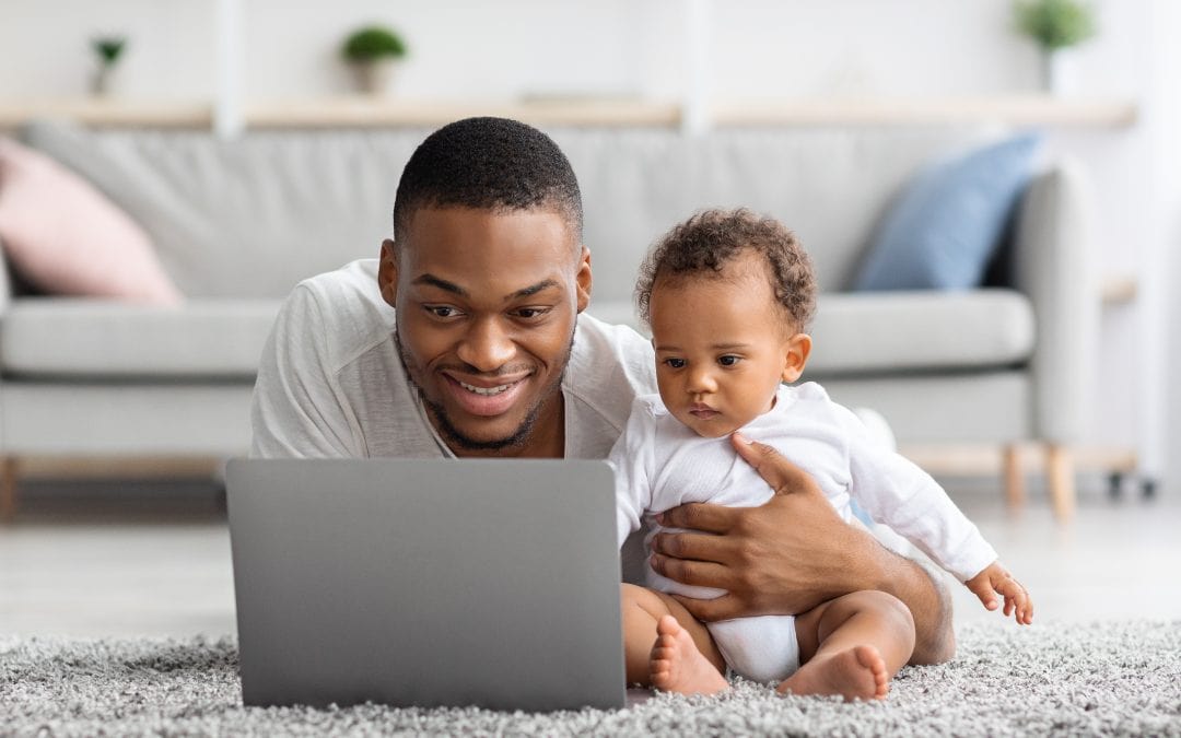 Un père et son bébé en train de traiter de démarches administratives sur l'ordinateur.